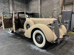 Cream-colored classic car inside a detailing shop